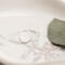 Single open circle sterling silver ring on white marbled dish with green leaf.

